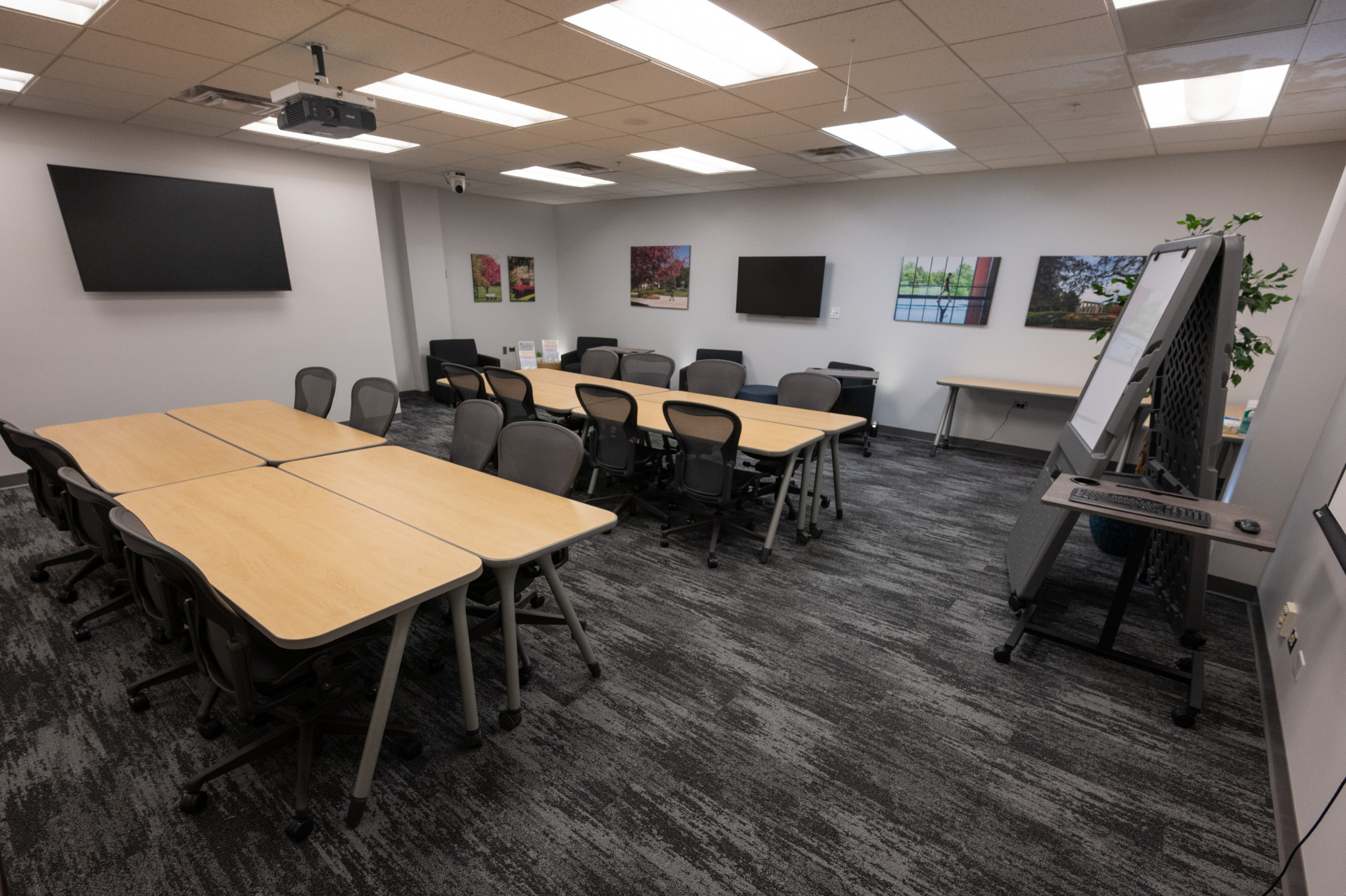 L243 instructional classroom viewed toward the projector screen, podium, and flexible tables